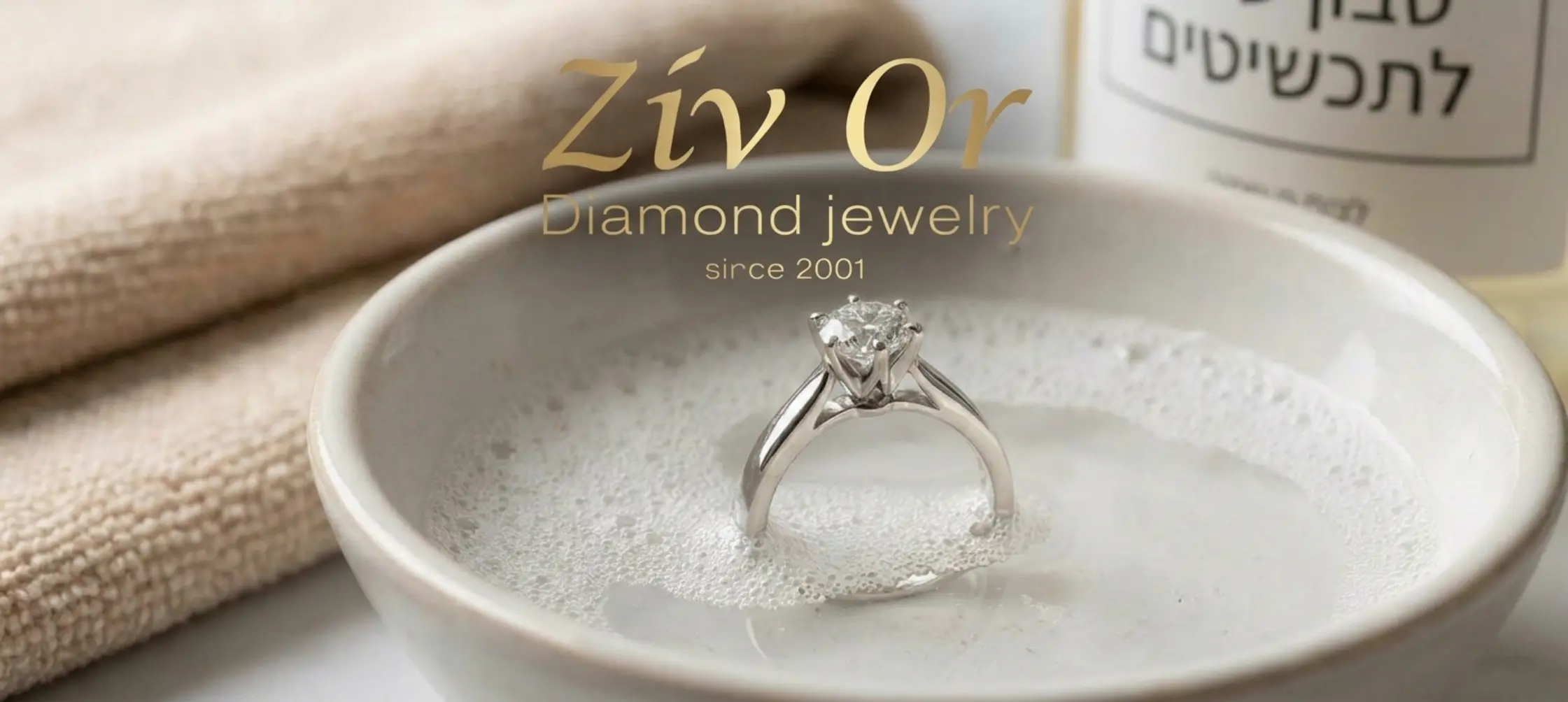 תקריב של טבעת אירוסין מזהב לבן בתוך קערה עם מים וסבון עדין כאשר ברקע רואים מטלית מיקרופייבר רכה מוכנה לייבוש הפריט