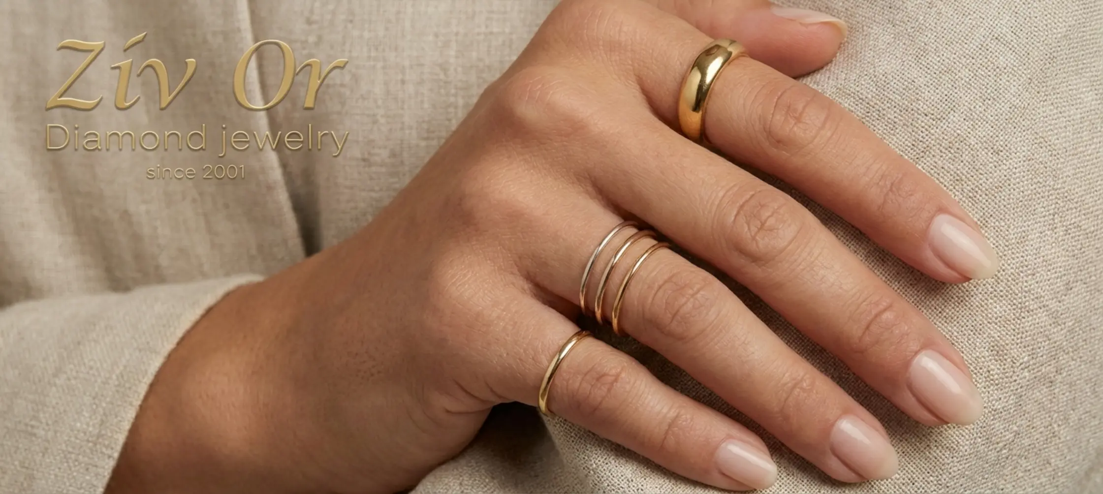 תמונה של כף יד נשית מעוצבת למשעי, עליה ענודות מספר טבעות בעוביים שונים מזהב צהוב ולבן. ניתן לראות אצבע אחת עם טבעת זהב עבה ולידה אצבע נוספת עם שלוש טבעות דקיקות ועדינות, כאשר הזרת נותרה ריקה מטבעות.