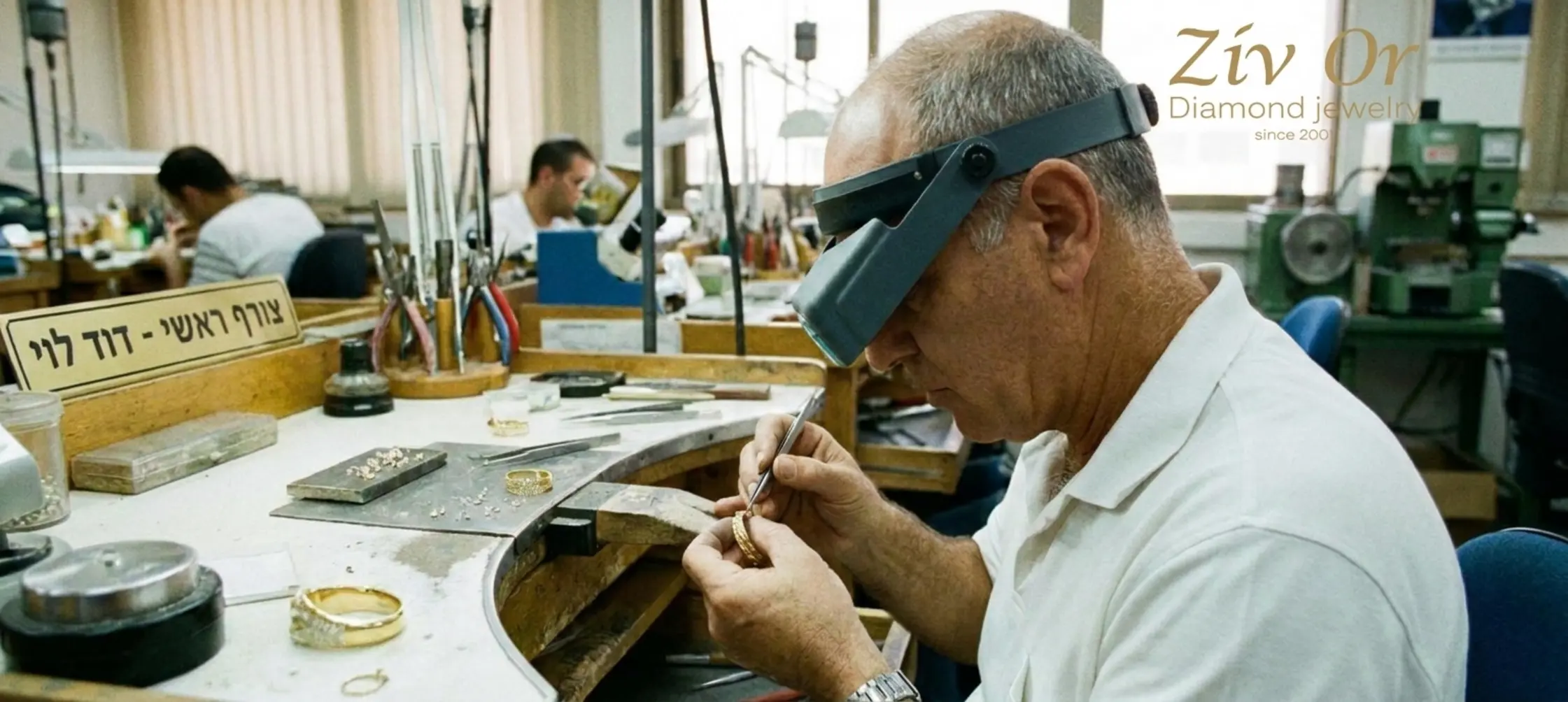 תמונה אותנטית של צורף מקצועי במפעל בבורסה ליהלומים, משבץ בעדינות וברמת דיוק גבוהה יהלומים קטנים לתוך איר קאף מזהב צהוב בעזרת זכוכית מגדלת ייעודית וכלי עבודה עדינים